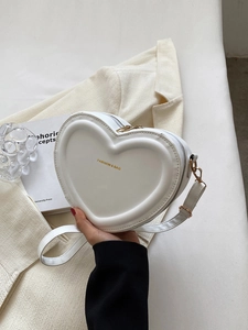 Détail d'un sac cœur en cuir PU blanc avec logo doré et bandoulière assortie élégante