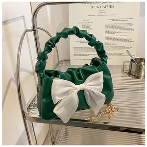 Detail of green ruched cloud bag featuring a large white organza bow and gold chain strap
