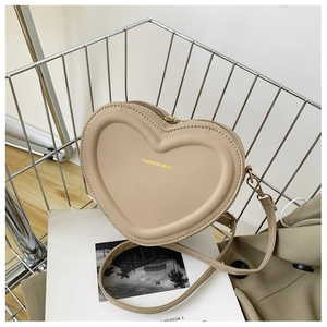 Détail d'un sac bandoulière beige en forme de cœur en cuir PU avec logo mode à l'avant