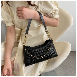 Detail of black textured PU leather shoulder bag with golden chain strap on model