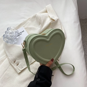Détail du sac à bandoulière en forme de cœur vert clair avec lettrage doré de mode