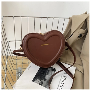 Détail du sac à bandoulière cœur marron foncé avec lettrage doré dans un chariot argenté
