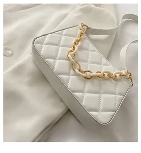 Détail de la texture matelassée blanche et de la chaîne en acrylique du sac à bandoulière