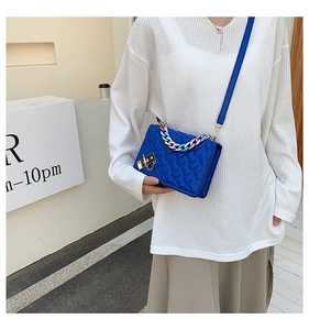 Detailed close-up of blue quilted leather bag featuring gradient chain and gold lock