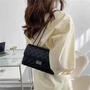 Classic black quilted chain bag with silver twist lock shown on model's shoulder