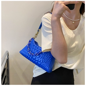 Close-up of royal blue pleated shoulder bag with resin chain and golden metal hardware