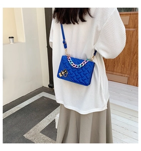 Detail of royal blue crossbody bag with quilted texture and colorful chain handle