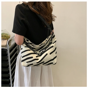 Detail view of large canvas tote bag with black zebra stripes and chunky chain strap