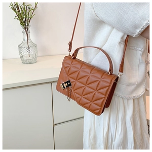 Detail of a brown quilted crossbody bag featuring a metal clasp and elegant chain accents