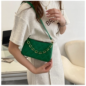 Détail d'un sac sous le bras matelassé vert avec chaîne épaisse porté par le mannequin