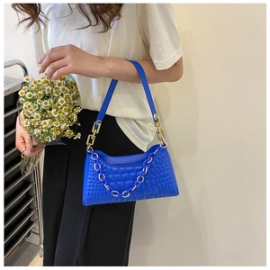 Close-up of vibrant blue baguette bag with gold and plastic chain details on model