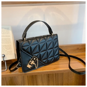 Close-up of black quilted leather handbag with gold metal clasp on a wooden shelf