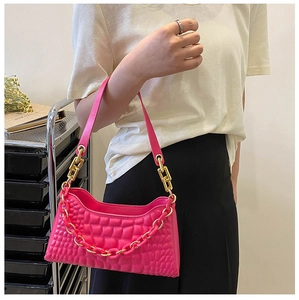 Detail of fuchsia underarm bag featuring chunky pink chain and textured block pattern