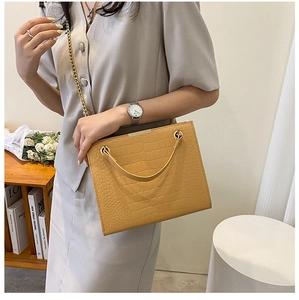 Detail of ginger yellow crocodile embossed leather tote with golden chain strap