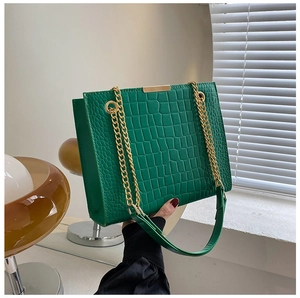 Detail of green crocodile texture shoulder bag with gold chain and metal buckle