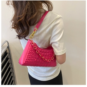 Detail view of pink crocodile embossed shoulder bag with gold chain strap on model