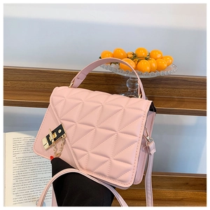 Pink quilted crossbody bag with golden chain lock shown on a stylish wooden staircase