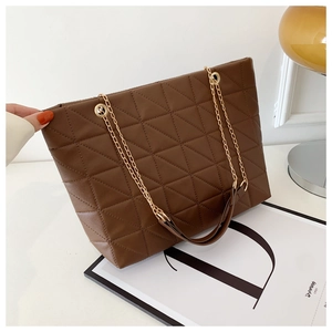 Détail d'un sac cabas marron matelassé avec chaîne dorée et texture cuir chic