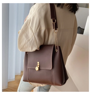 Detail of coffee brown vintage leather crossbody bag with white stitching and gold clasp