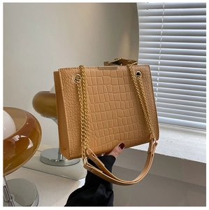 Detail of light brown crocodile texture handbag with gold metal chain straps and hardware