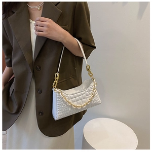Detail of white quilted baguette bag with thick gold chain and stylish leather handle