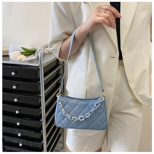 Détail du sac sous le bras matelassé bleu clair avec grosse chaîne dorée et bleue