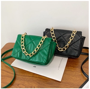 Détail de sacs matelassés en vert émeraude et noir avec poignées en chaîne dorée