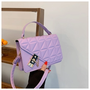 Close-up of purple quilted crossbody bag with gold lock and elegant chain detail