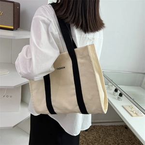 Large capacity canvas tote bag with fashion print and black handles on a female model