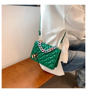 Close-up of bright green quilted bag with chunky rainbow chain and golden buckle