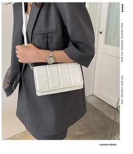 Detail of white quilted crossbody bag worn with a gray suit for a minimalist style