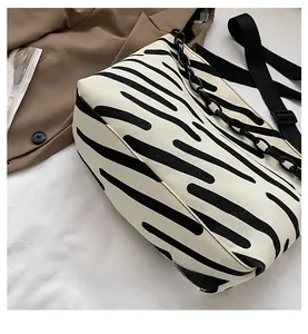 Detail shot of canvas tote featuring black and white stripe pattern with a metal chain