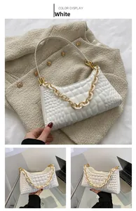 Close-up of white quilted baguette bag featuring a bold bi-color chunky chain accessory