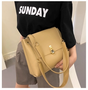 Detail of khaki leather crossbody bag featuring gold circular twist lock and chain strap