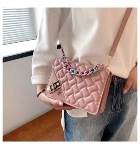 Detail of light pink crossbody bag featuring woven texture and gradient metal chain handle