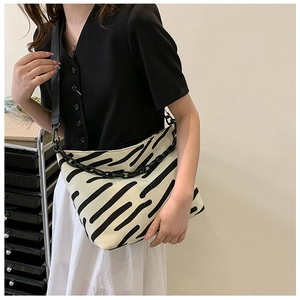 Detail of striped canvas tote bag with chunky black chain and wide shoulder strap