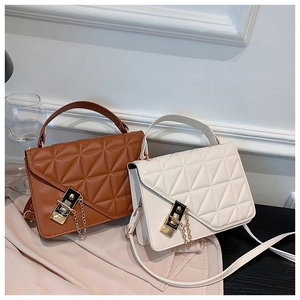 Detail view of brown and cream quilted bags with gold chain locks and elegant handles
