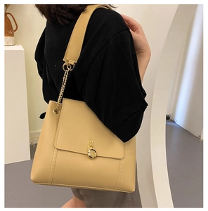 Detail of khaki leather tote bag featuring a round metal clasp and chain strap