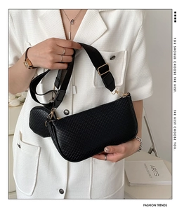 Detail of black woven shoulder bag with small round coin purse and gold hardware accents