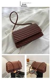 Detail of a dark brown quilted shoulder bag with golden cylindrical metal hardware