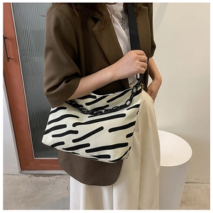 Detail of zebra pattern canvas tote featuring chunky black chain and wide shoulder strap