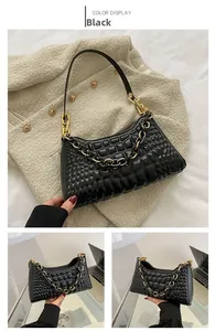 Detail of black underarm bag featuring diamond lattice texture and golden chunky chain