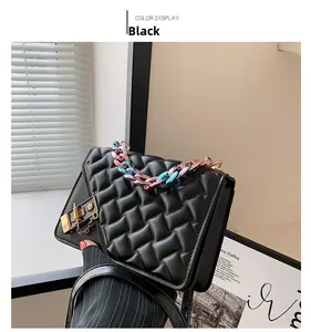Close-up of black quilted leather handbag featuring a gradient metal chain and gold lock