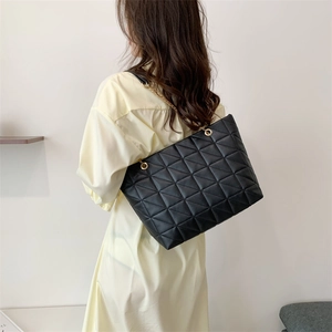Sac cabas matelassé avec chaîne dorée porté par un mannequin en style décontracté