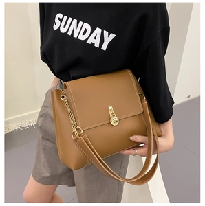 Detail view of brown crossbody bag featuring gold twist-lock and decorative white stitching