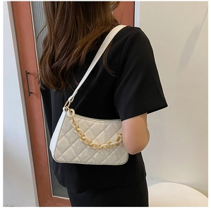 Détail du sac sous l'aisselle matelassé blanc avec chaîne décorative en or et acrylique