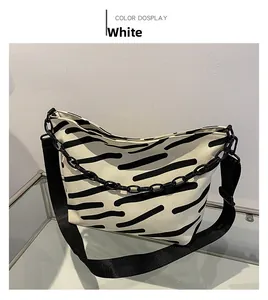 Detail of zebra-striped canvas tote bag with decorative black chain and adjustable strap