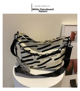 Detail view of canvas tote bag with black abstract brushstrokes and chain charm