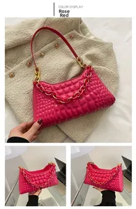 Detail of rose red underarm bag with quilted texture and gold chunky chain strap
