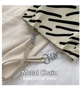 Detail of the durable silver hardware chain and striped canvas texture of this tote bag